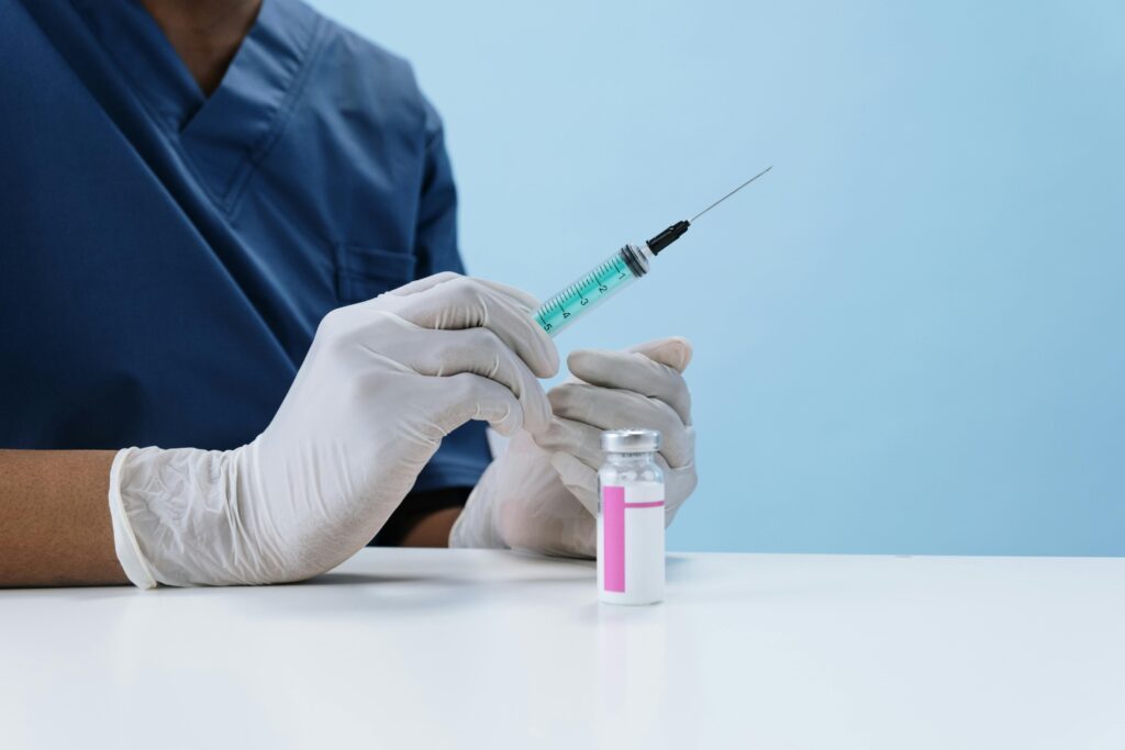 Close-up of a healthcare professional filling a syringe with vaccine from a vial.
